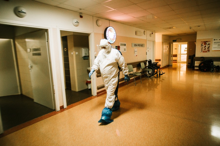 Szpital Zakaźny w Bydgoszczy, pracownik szpitala idący przez pusty korytarz izby przyjęć, ubrany w uszczelniony kombinezon, fot. Filip Kowalkowski dla UMWKP