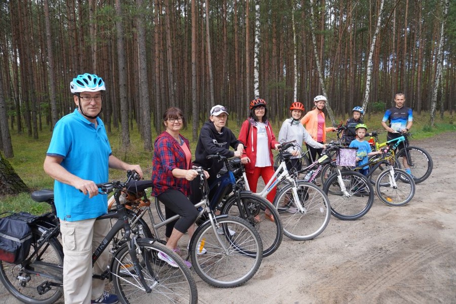 Stojący z rowerami uczestnicy wyprawy na leśnej drodze, przygotowani do dalszej wycieczki.