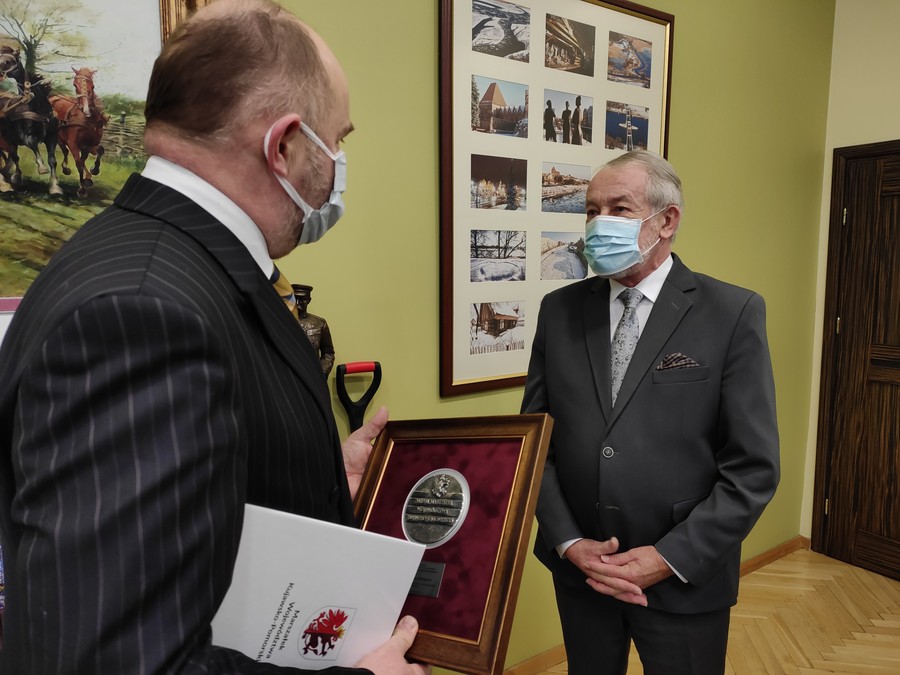 Marszałek Piotr Całbecki przekazuje medal synowi pani Anieli Mikołajczak, fot. UMWKP