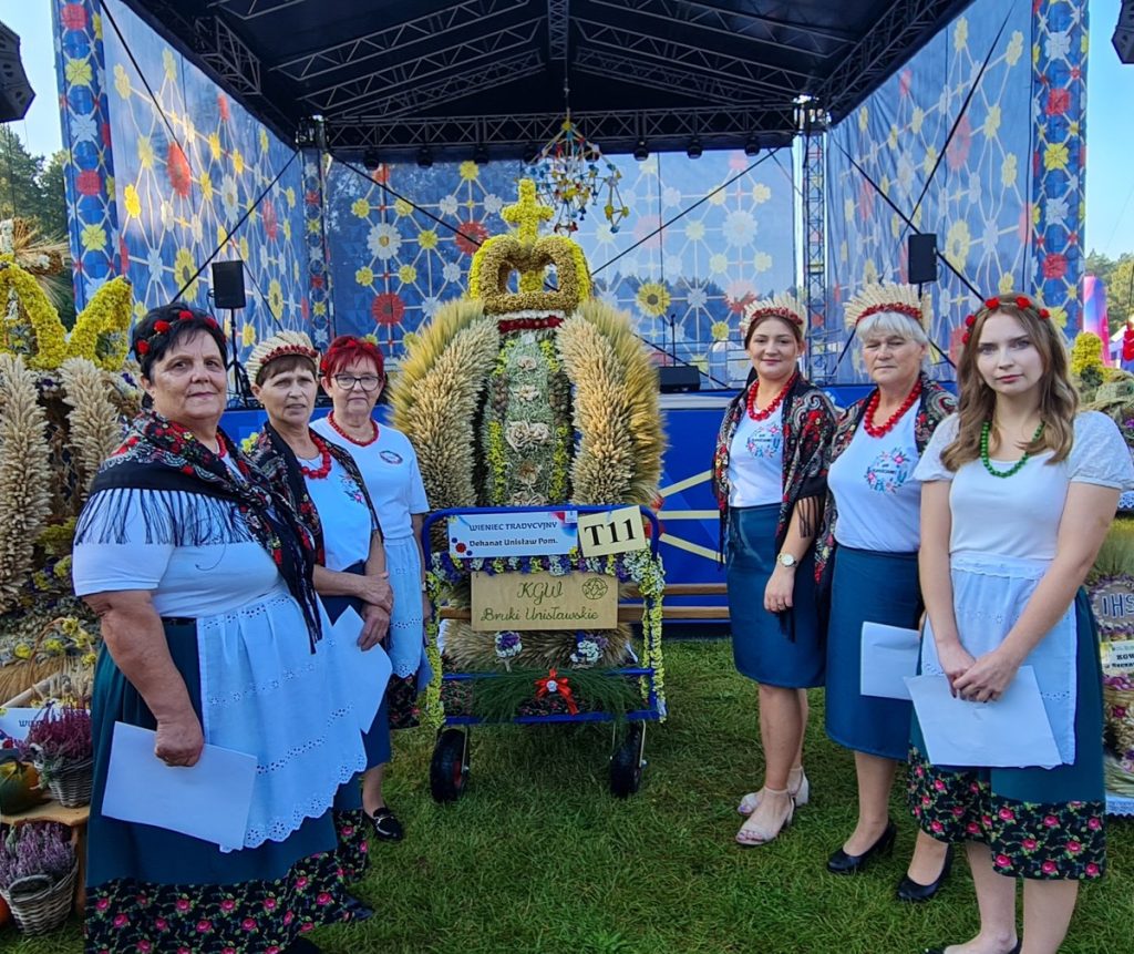 Panie z KGW z Bruków Unisławskich w strojach tradycyjnych na tle tradycyjnego wieńca dożynkowego